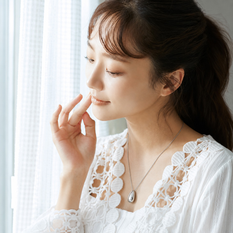 窓辺でホイッスルネックレスを着用する女性の着用イメージ